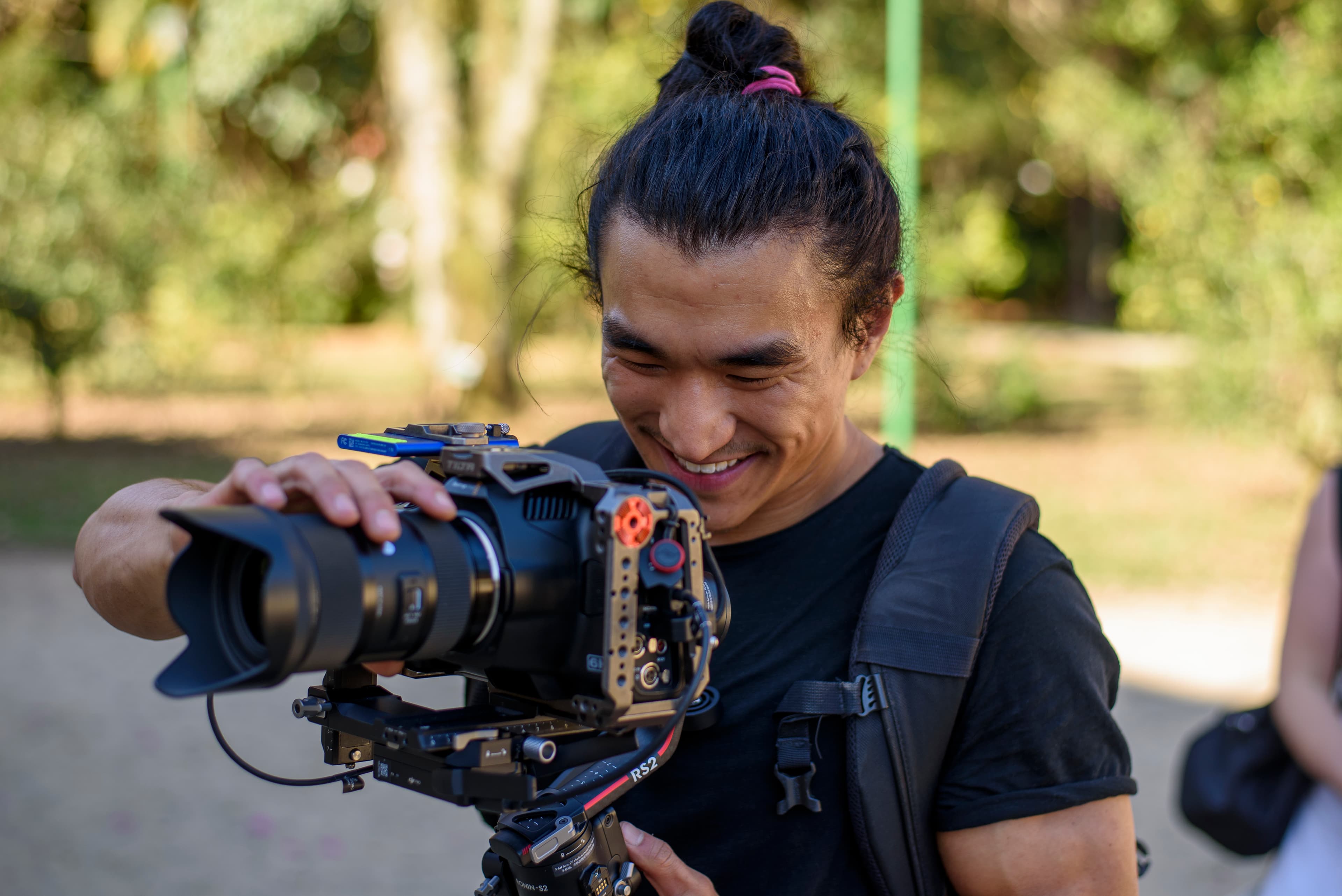A professional portrait of Lucas Hashimoto on a film set, operating a camera.
